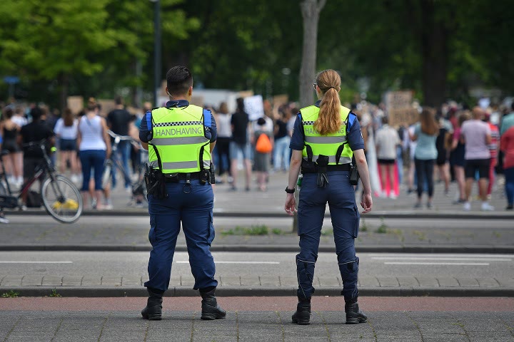 Twee handhavers in veiligheidsvest bij een menigte